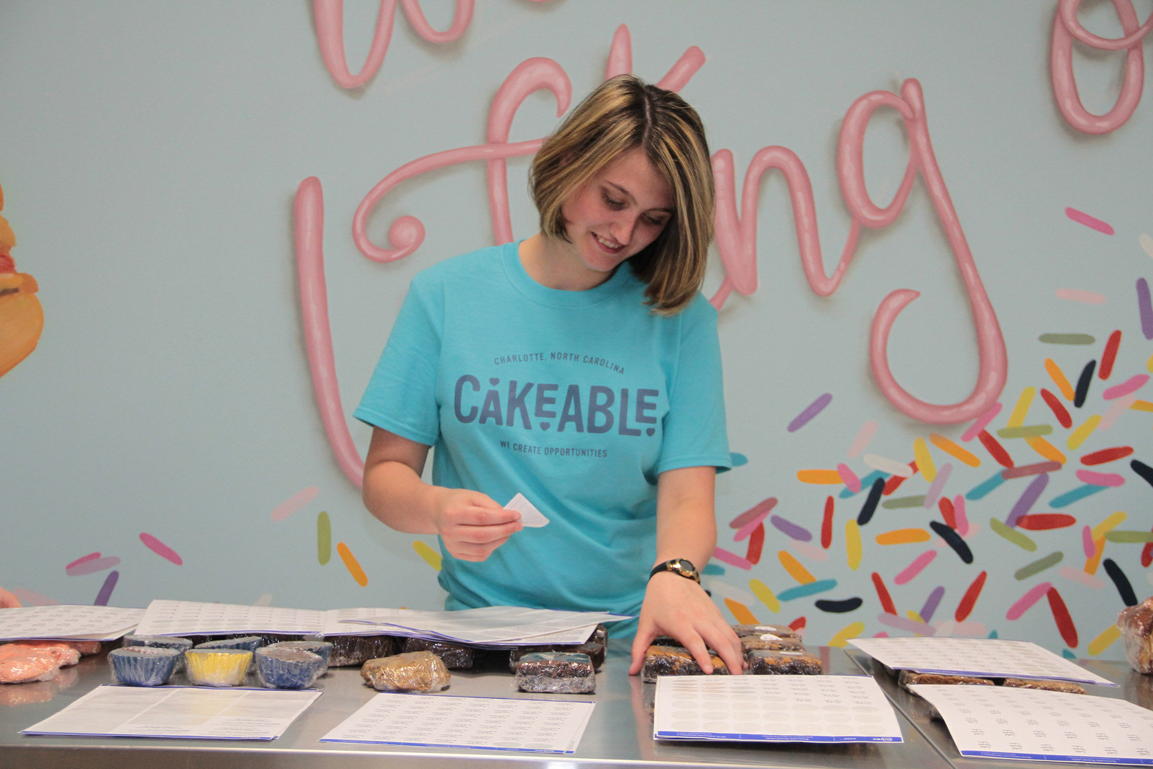 A Cakeable team member labelling packaged baked goods at a work table