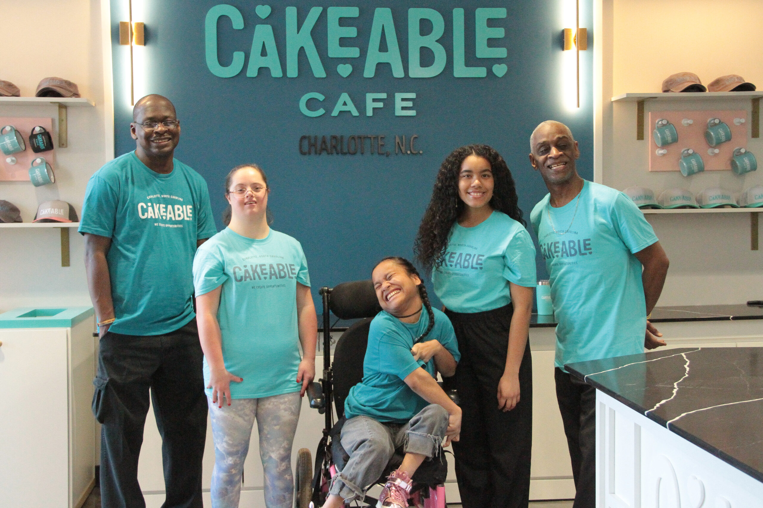 Five Cakeable team members gathered in front of the Cakeable Cafe sign