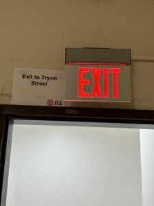 An illuminated EXIT sign beside a placard reading Exit to Tryon Street